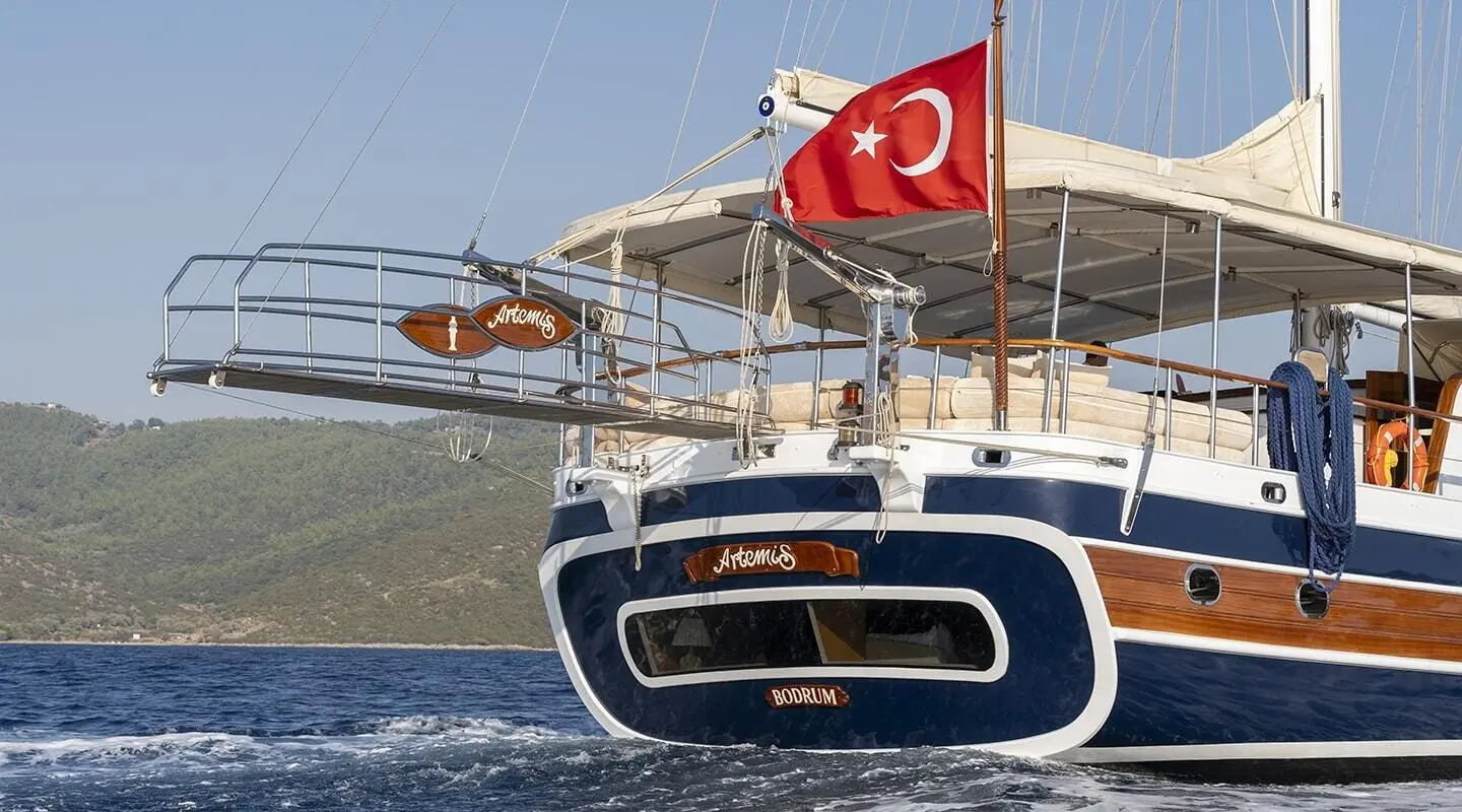 Artemis luxury yacht with red Turkish flag, stern view at sunset harbor