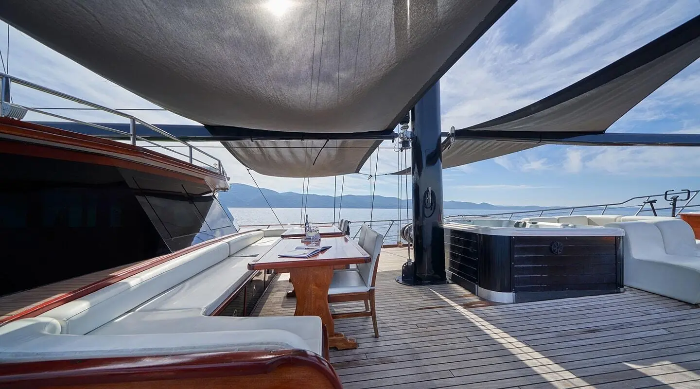 Yacht Stella Maris lounging area with wooden deck and shaded seating at sunset