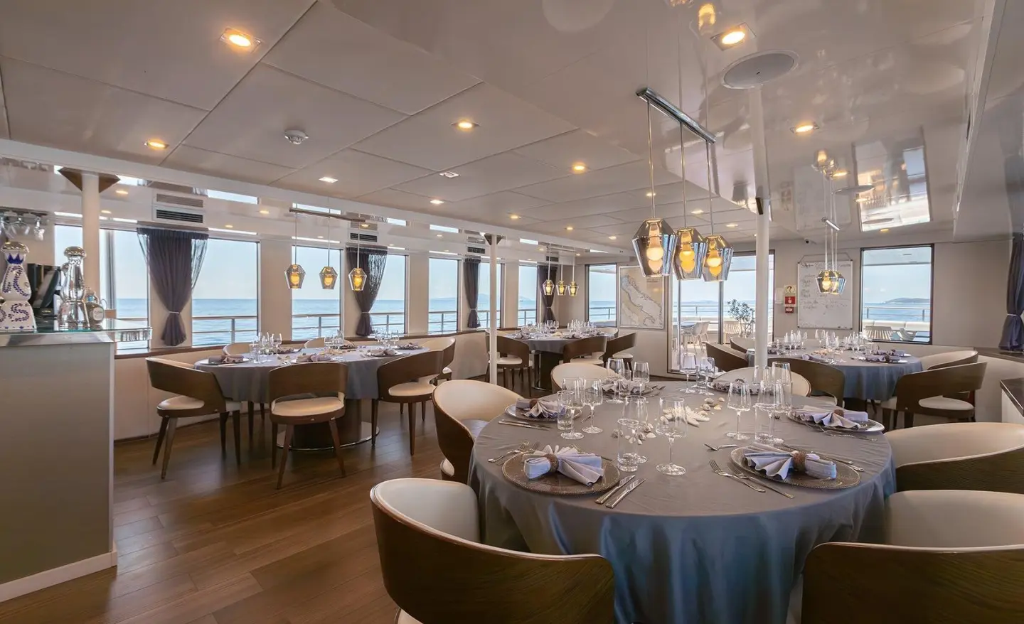 Dining salon on luxury yacht YOLO with tables set for dinner and warm lighting