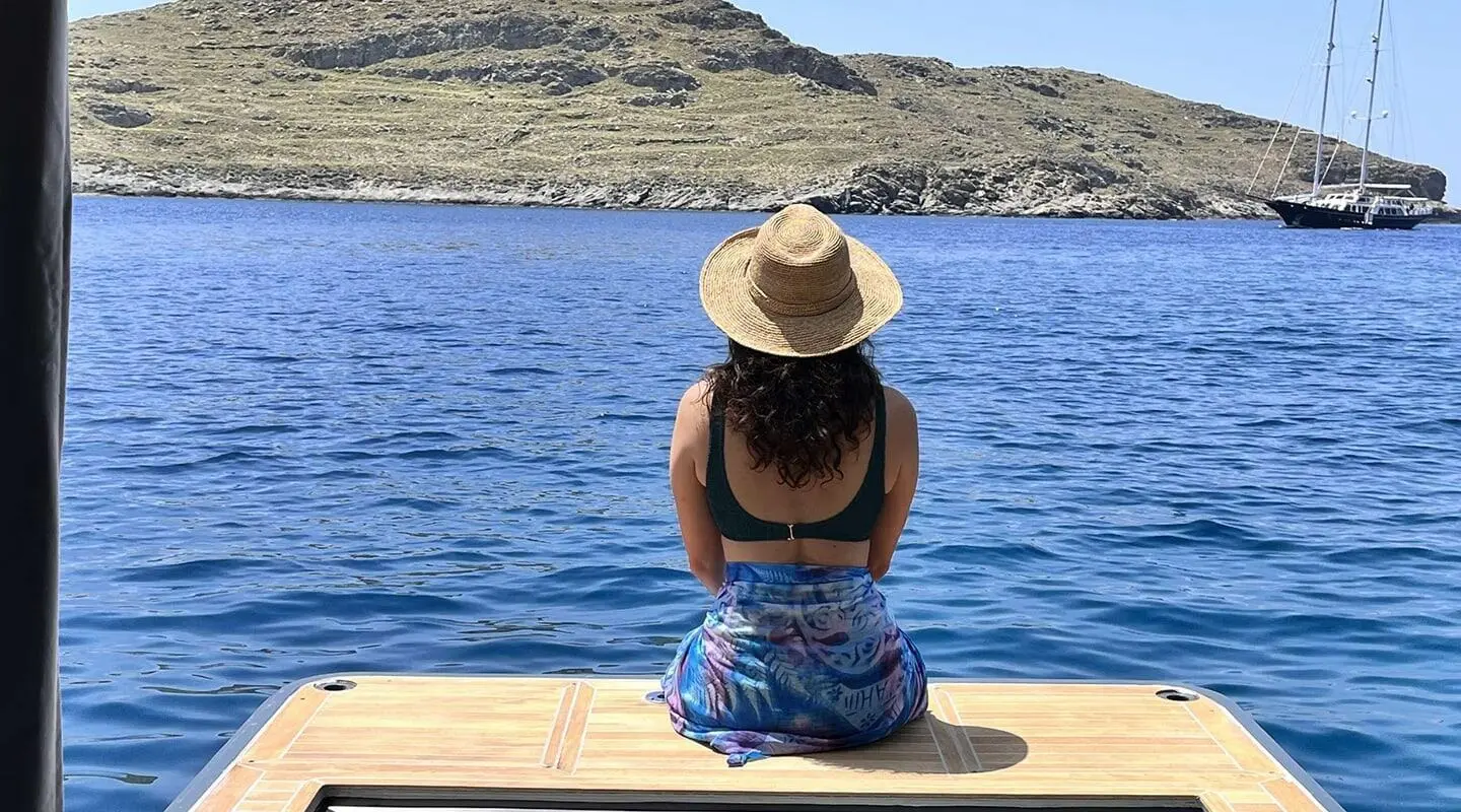 Woman sitting on a yacht platform by the blue sea