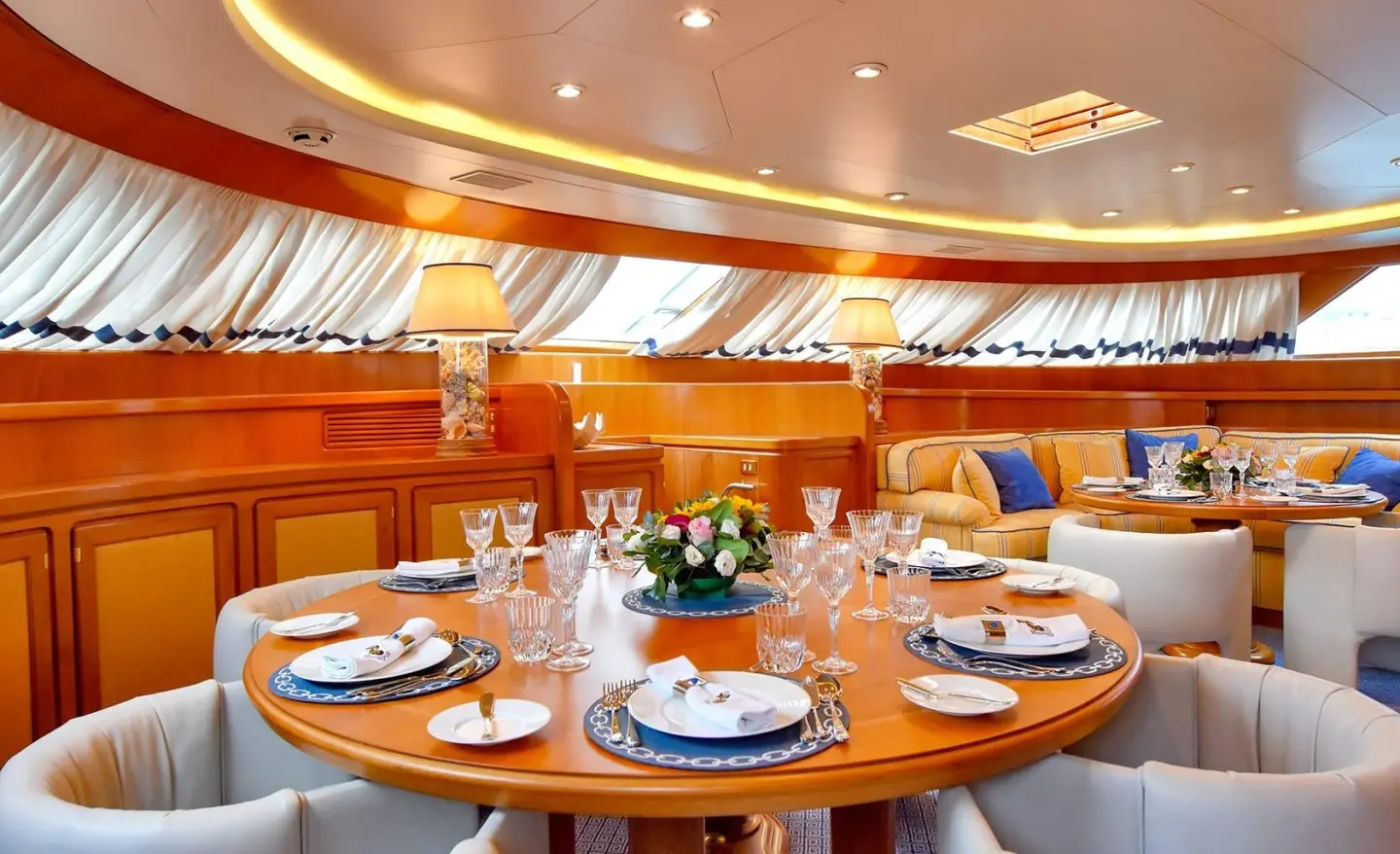 Deck dining area on Tamarita yacht with round table setting and white chairs