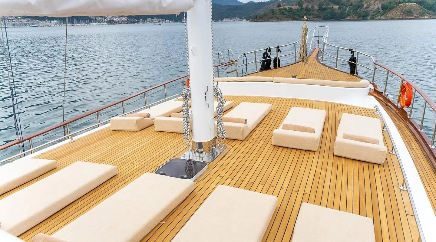 Sunlit teak deck of Happy Days yacht with lounge cushions and railing