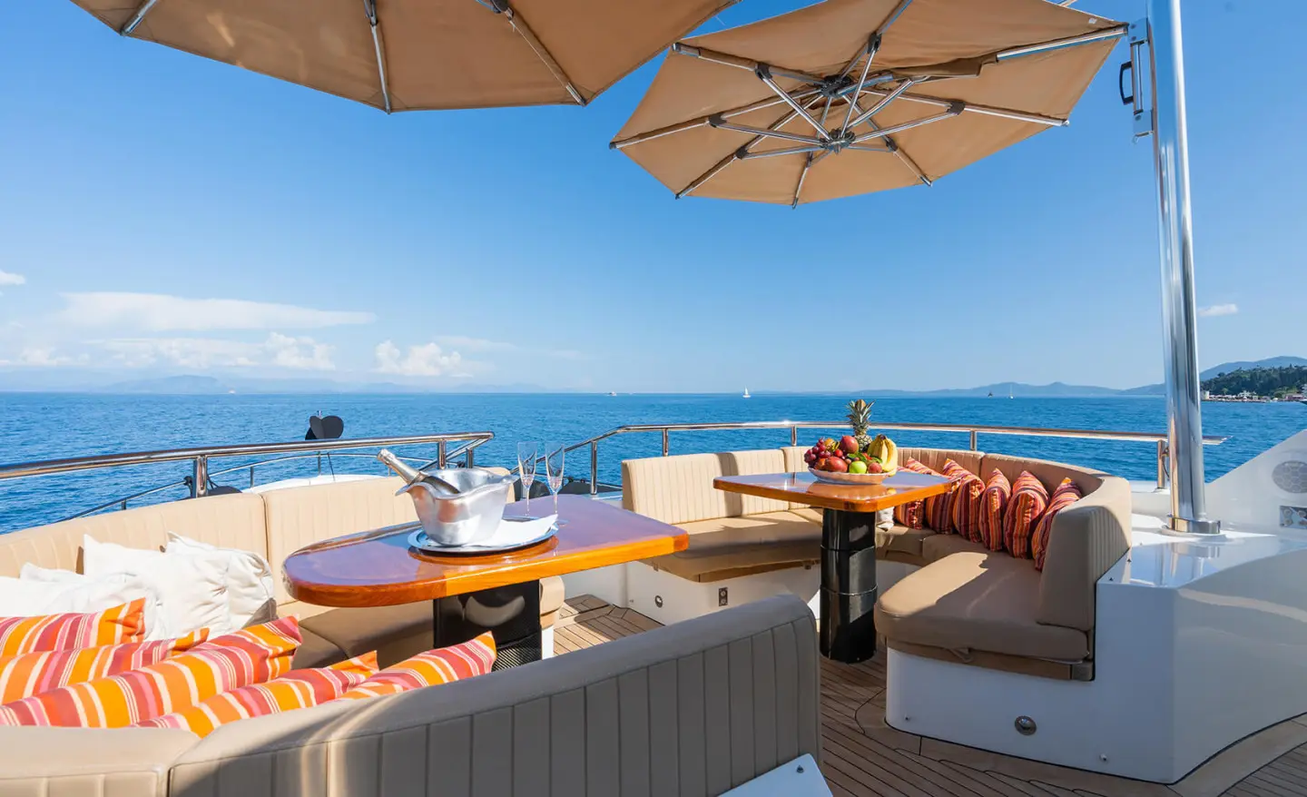 Serenity yacht deck with seating, umbrellas, and ocean view at sunset