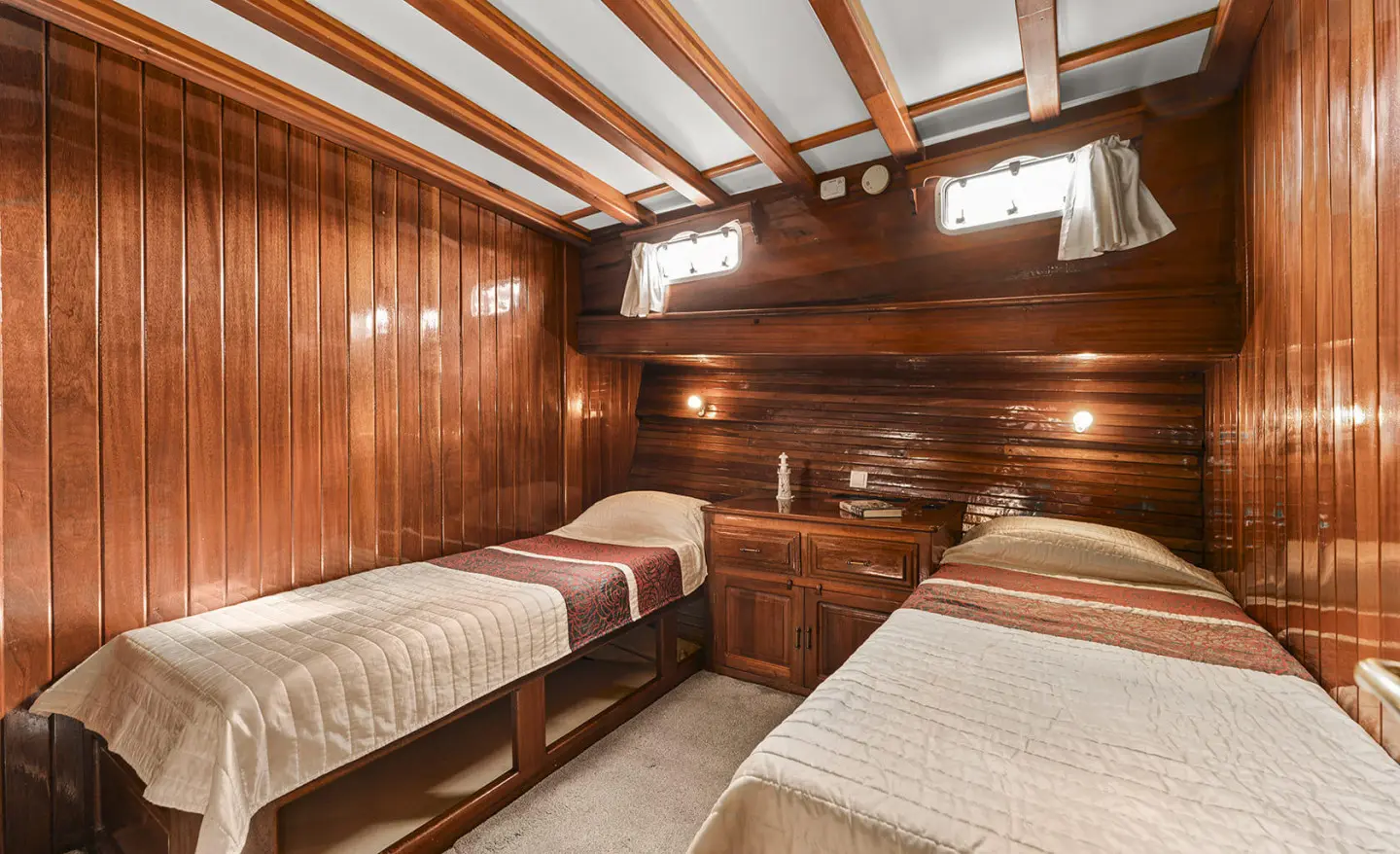Two twin cabins aboard a wooden yacht interior with portholes and bunk beds