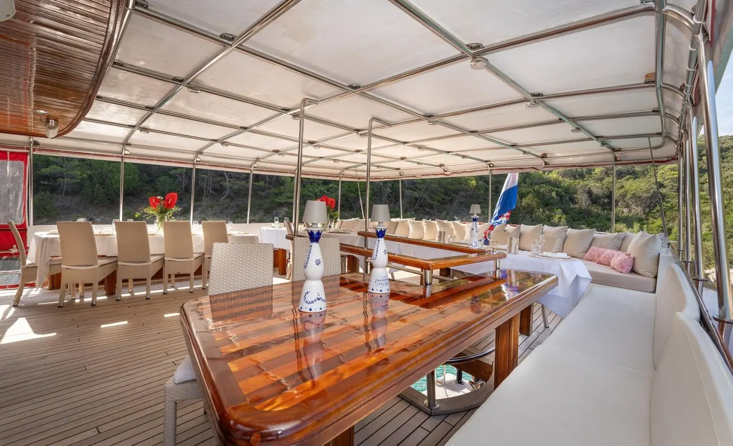 Aft deck of Barbara yacht with wooden table, chairs, and canopy overhead