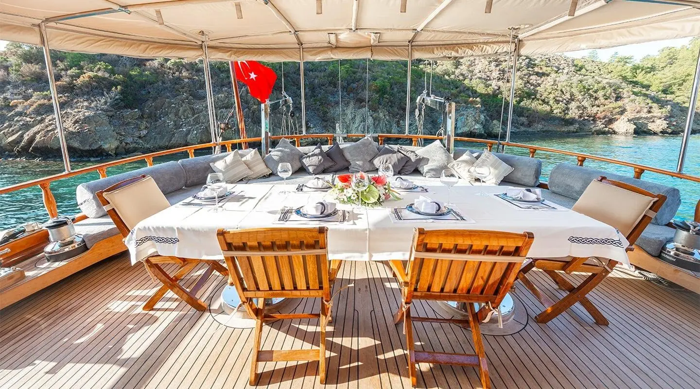 Ros Mare yacht party table setup on deck at sunset, wooden chairs and plates