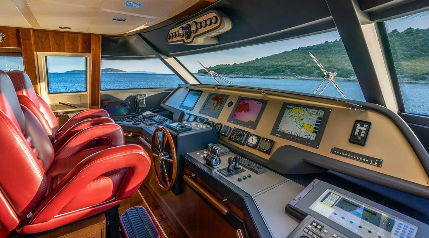 Red leather seats and helm with navigation screens and sea view through windows