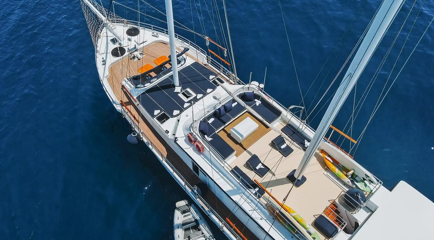 Aft deck of Aurum gulet with wooden decking, blue sails furled, sunlit