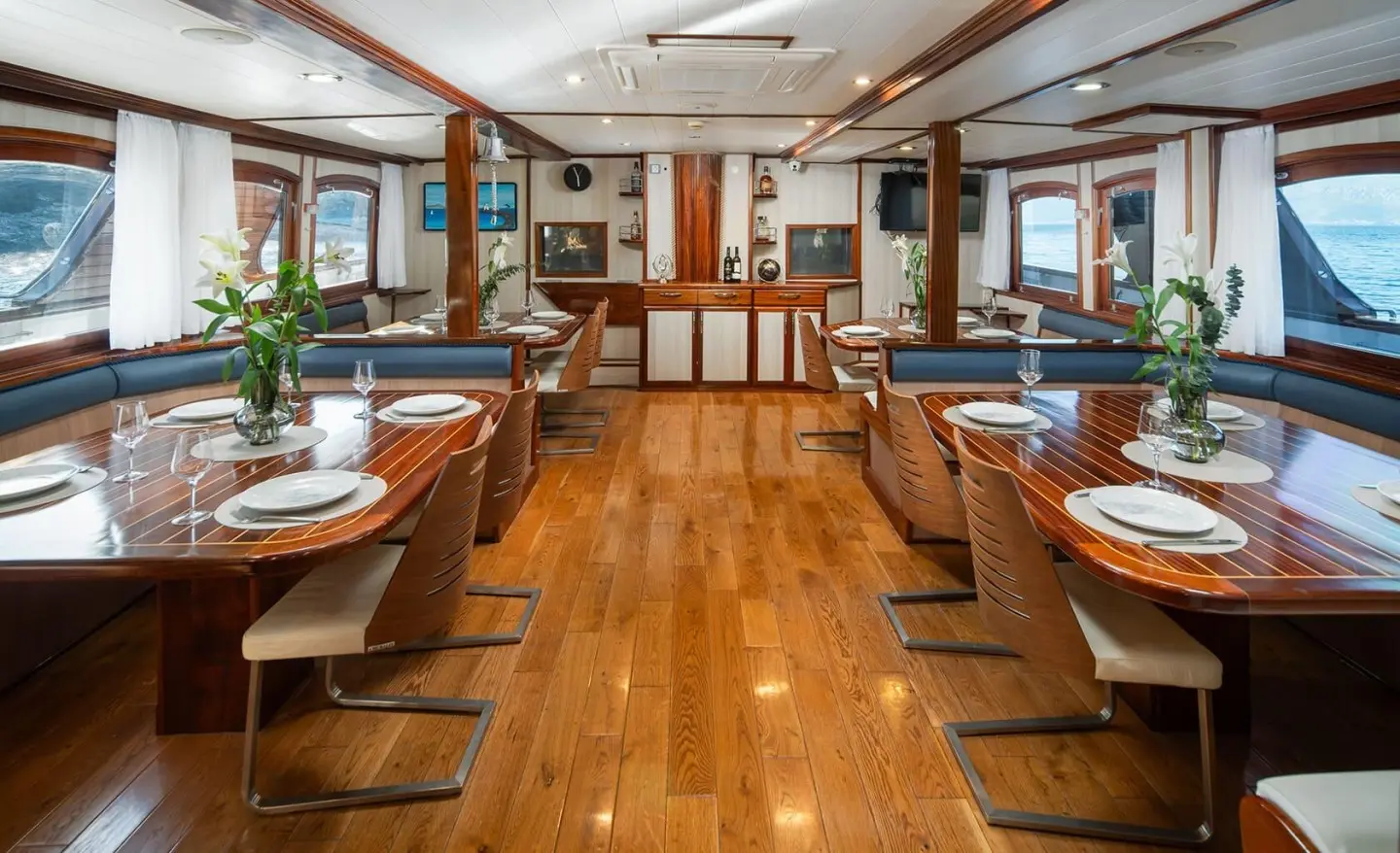 Mendula yacht interior with polished wooden dining tables and chairs aboard