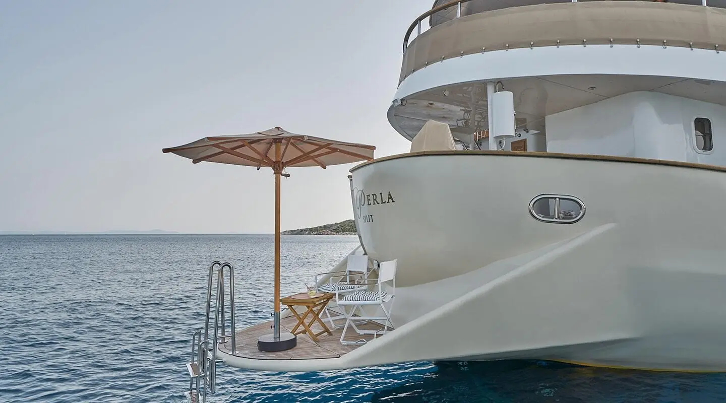 La Perla luxury yacht seen from stern with deck seating and umbrella above water