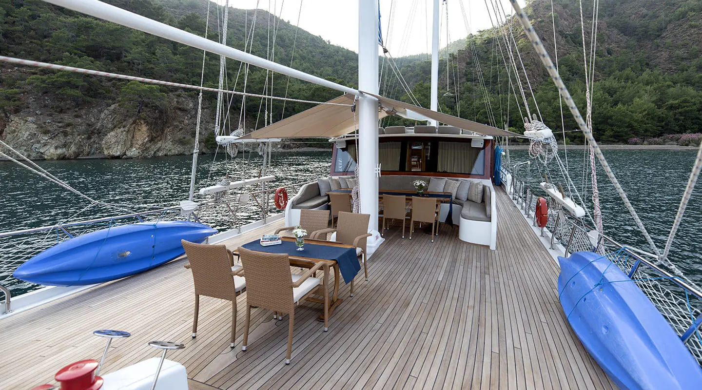 Kayhan 5 yacht on a wooden deck at sunset with chairs and shaded seating