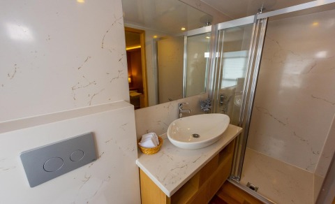 Simay M luxury yacht bathroom with marble walls, oval sink, and glass shower door