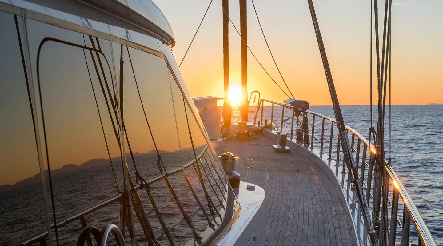 Sunset on Long Island schooner deck with polished rails and rigging reflected in windows
