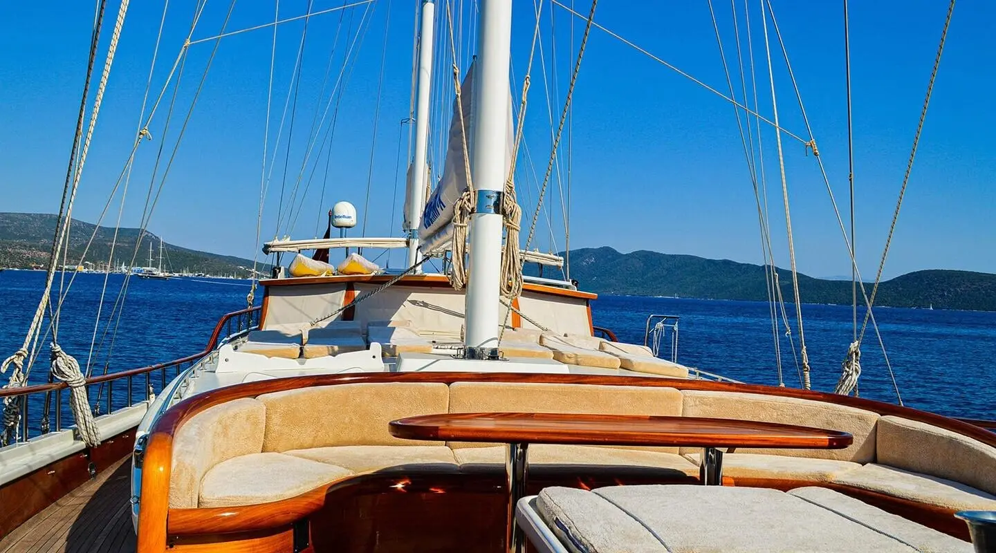 Enderim A yacht deck with ropes, wooden seating, and blue sea horizon at sunset
