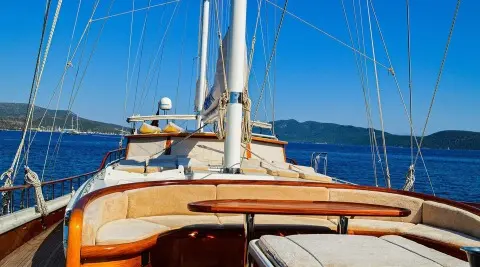 Enderim A yacht deck with ropes, wooden seating, and blue sea horizon at sunset