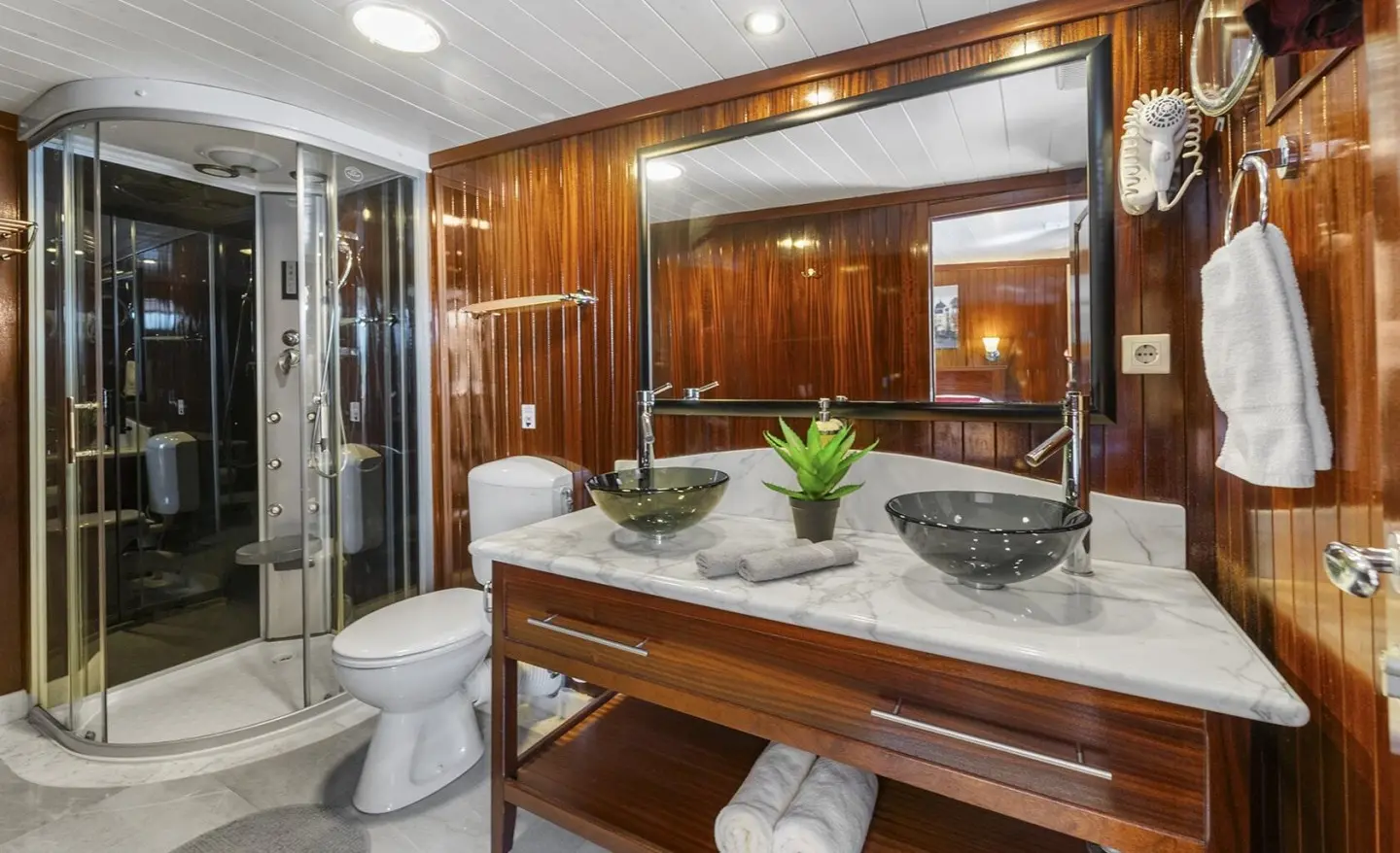 Cesarica yacht bathroom with marble vanity, dark vessel sinks, wooden panels