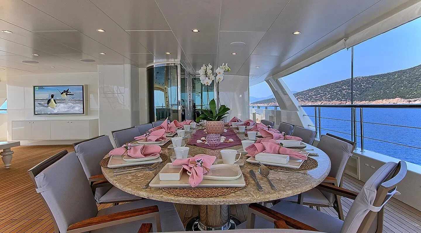 Table set for a yacht interior with pink napkins and flowers aboard Meira