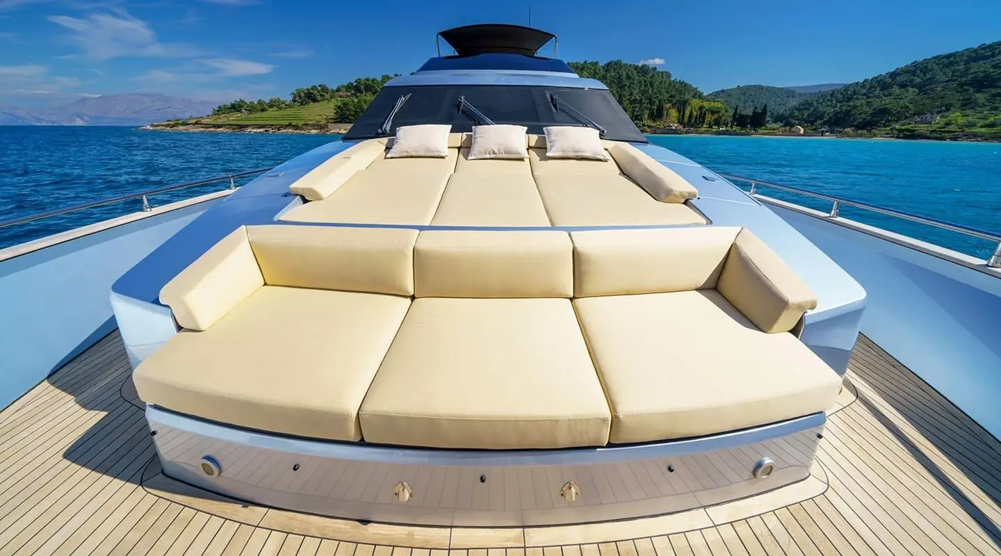 Phantom yacht sunpad and cream cushions on bow with turquoise sea and coastal hills