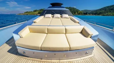 Phantom yacht sunpad and cream cushions on bow with turquoise sea and coastal hills