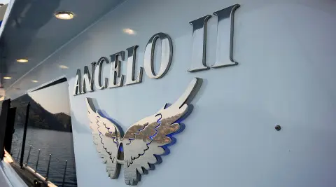 Angelo II yacht name and silver wing emblem on light blue hull exterior