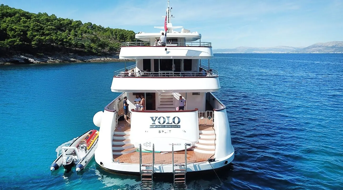 Back view of Yolo yacht at sea with white hull and blue water
