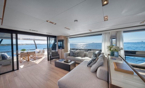 Bright saloon interior with light-colored furniture and large windows overlooking the sea