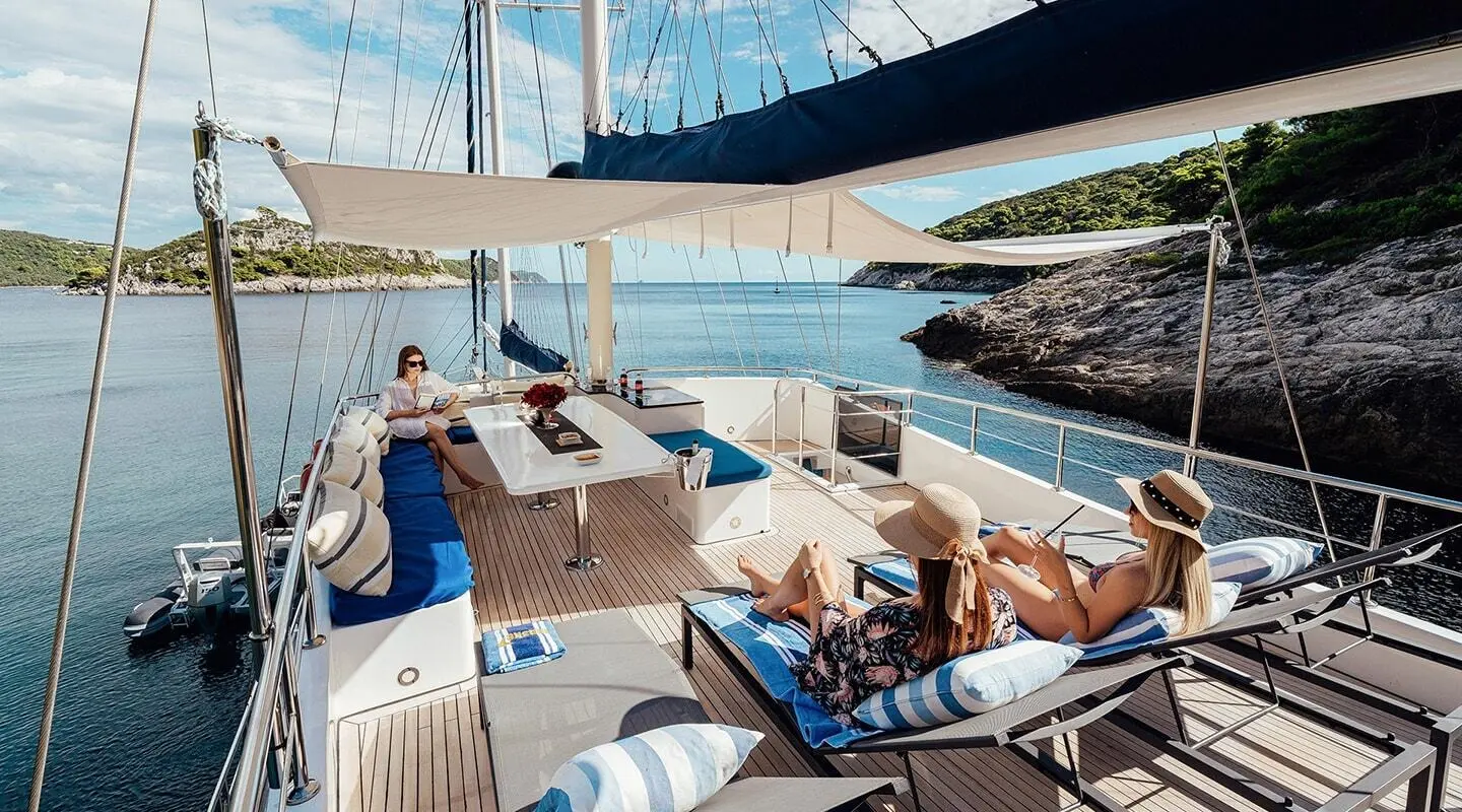 Maske luxury gulet yacht deck with sun loungers and people relaxing onboard