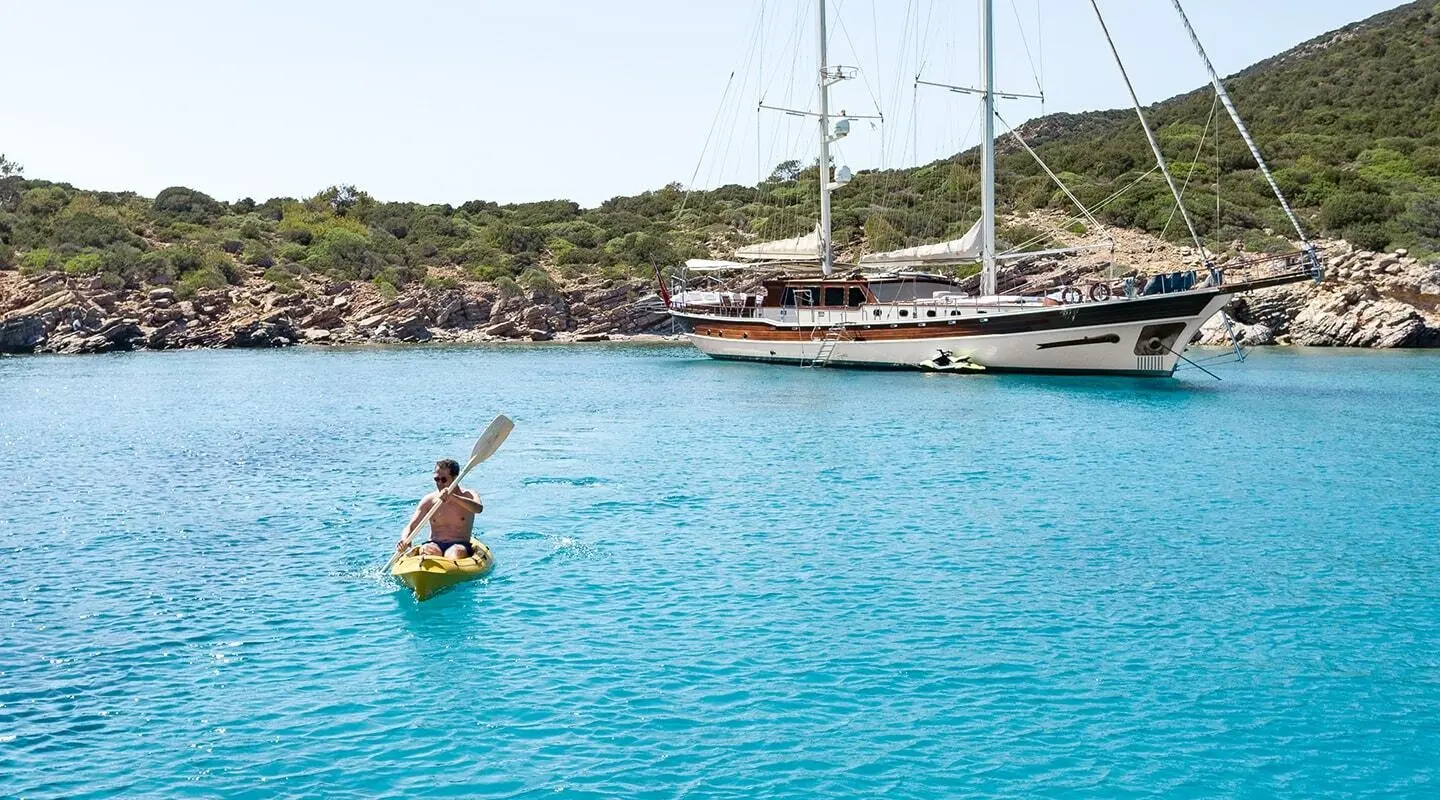 Estrella De Mar gulet anchored in turquoise bay with people kayaking nearby
