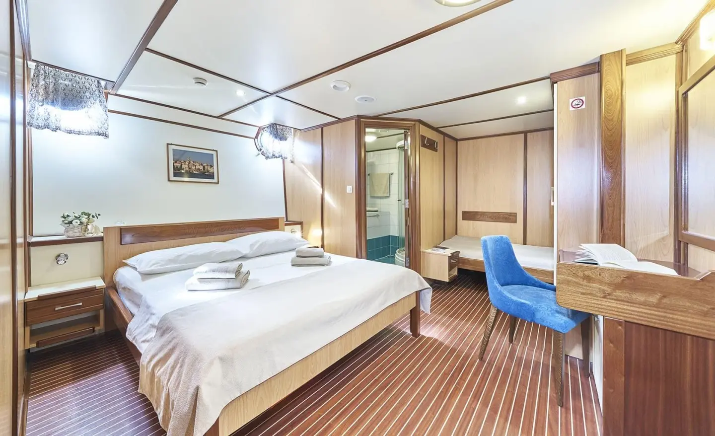 Amorena yacht deck view: spacious interior with bed, seating, and wooden flooring