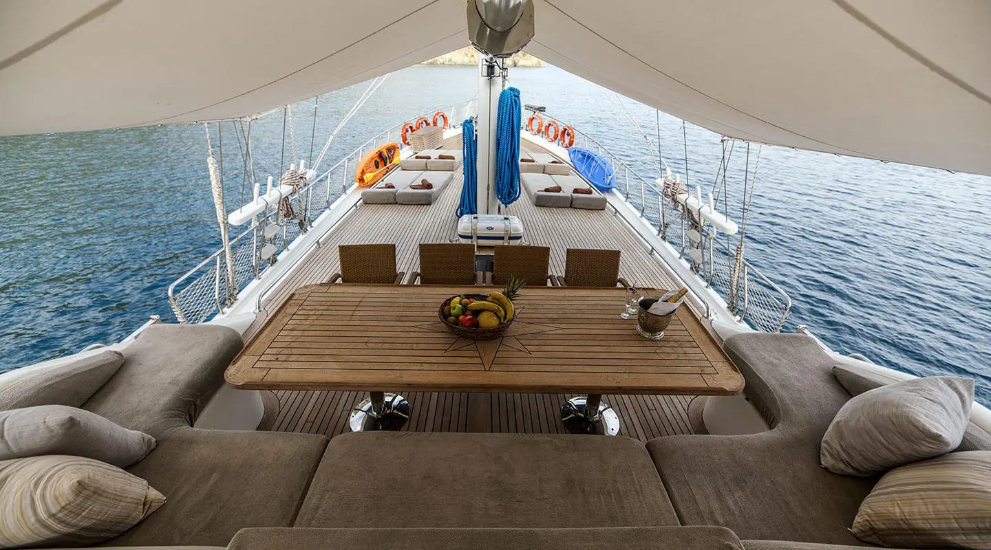 Kayhan 3 yacht deck setup with cushioned seating under a canopy at sunset