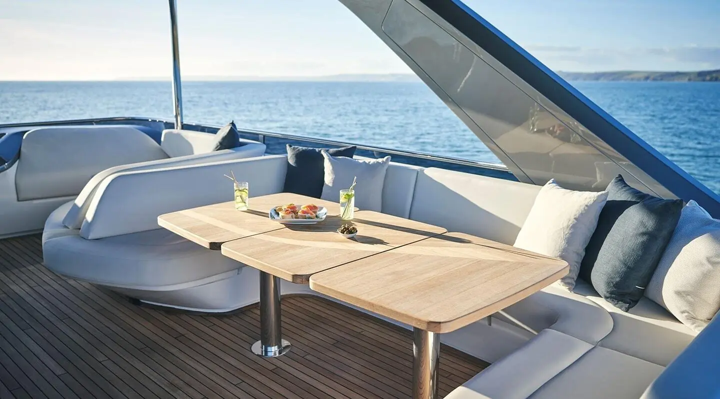 Elegant yacht Elizabeth deck with wooden table and sun loungers overlooking calm sea