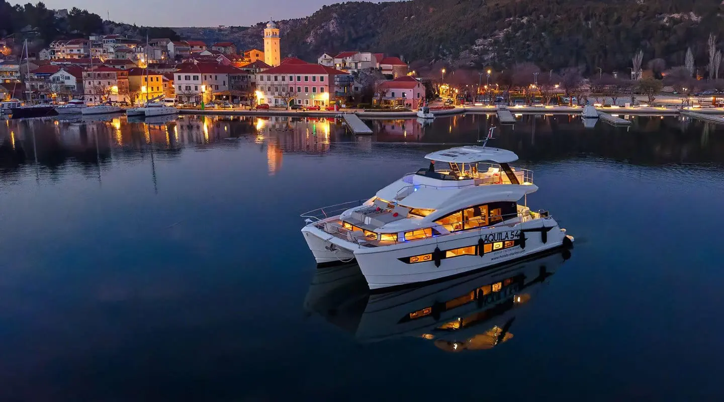 Yacht named By My Side anchored at sunset with calm water reflections