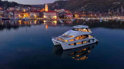 Yacht named By My Side anchored at sunset with calm water reflections
