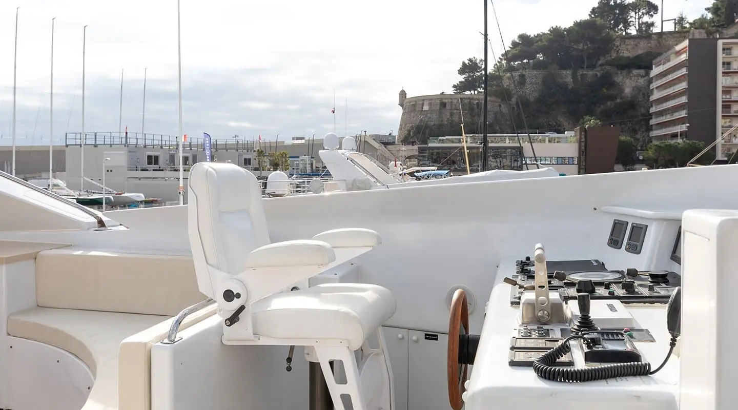 Yacht Brooklyn cockpit with white chairs and table on deck near a harbor