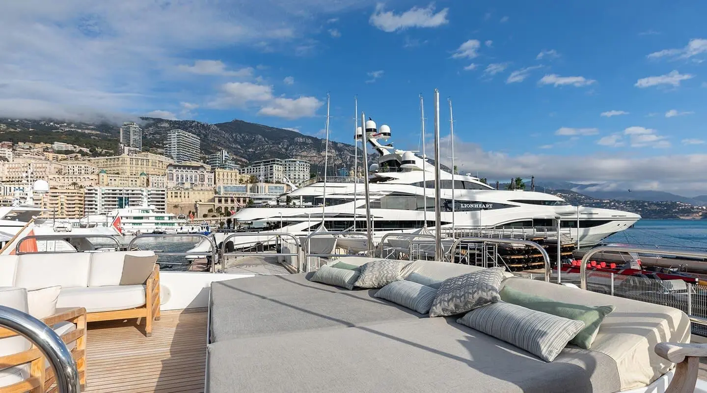 Yacht Brooklyn with flybridge and stacked moored boats at a marina under blue sky