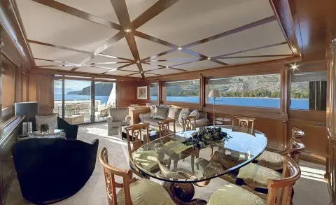 Aquila yacht saloon interior with wooden ceiling fans, dining table, and seating