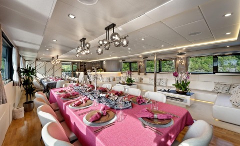 Freedom yacht dining interior with pink and gray table setting and plush seating