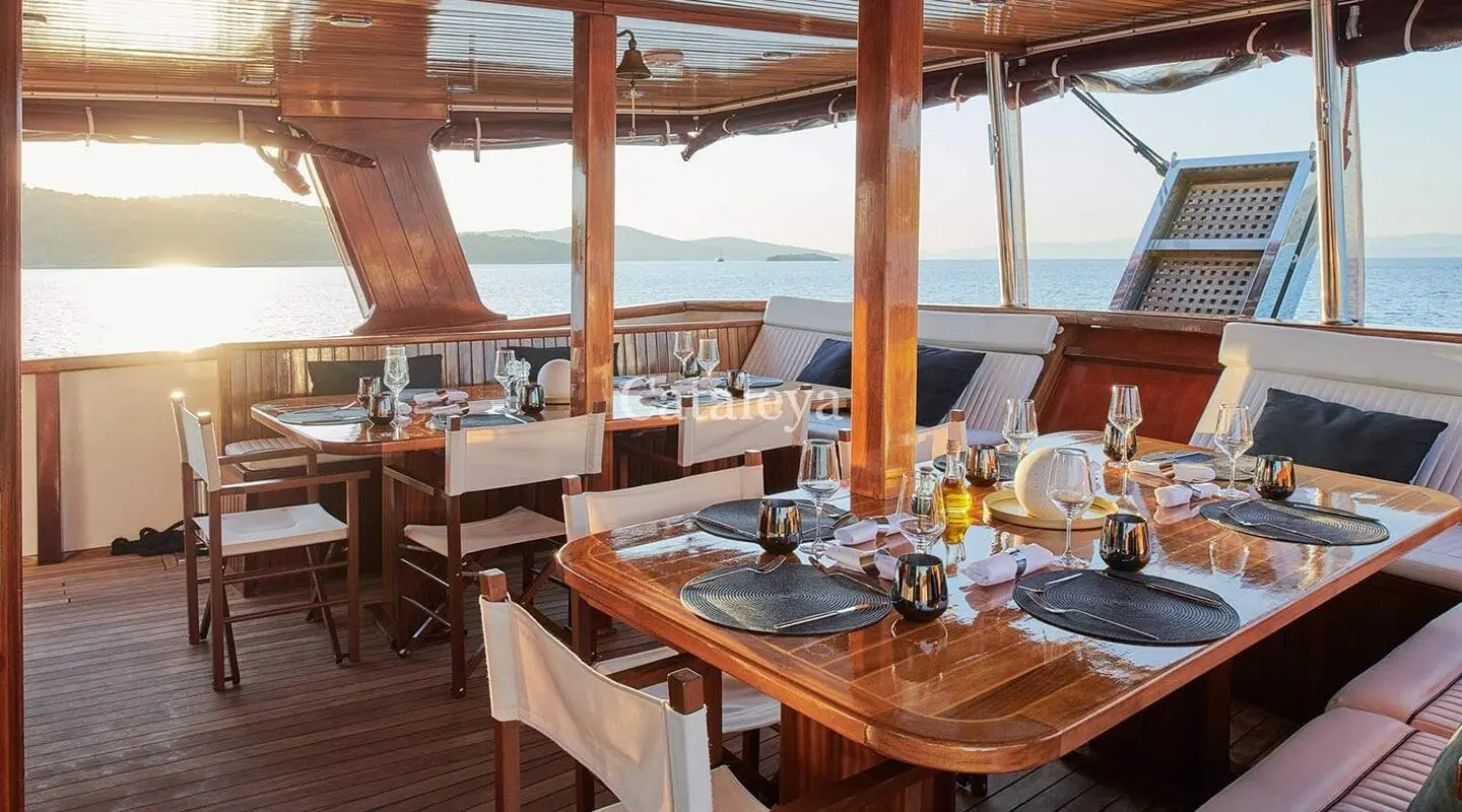 Yacht Cataleya dining deck aboard a luxury gulet with wood framing and sunset horizon