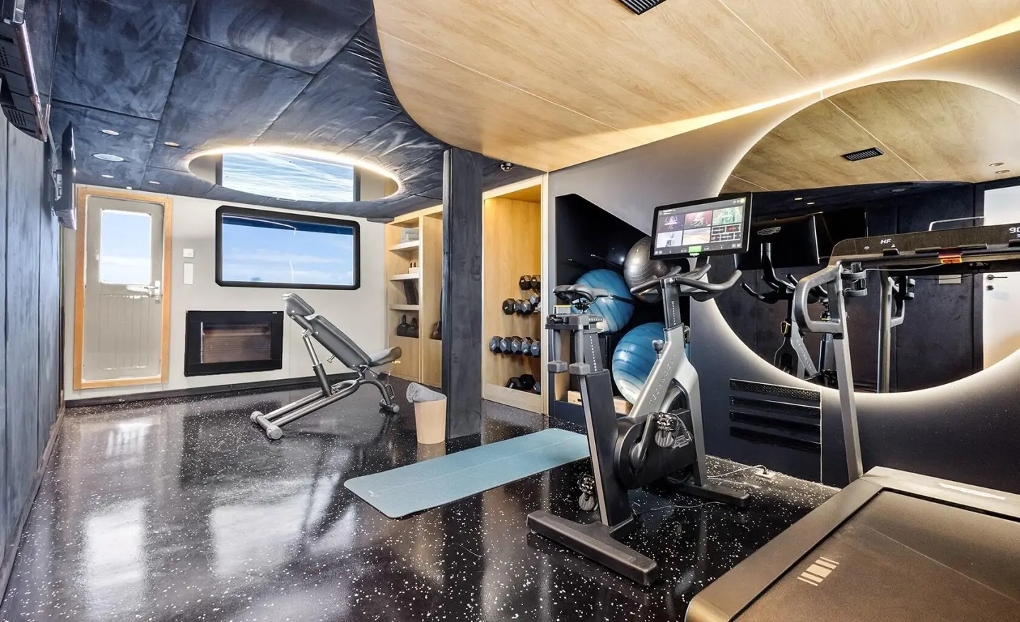 Interior view of Bella yacht gym with treadmill, weights, and workout area