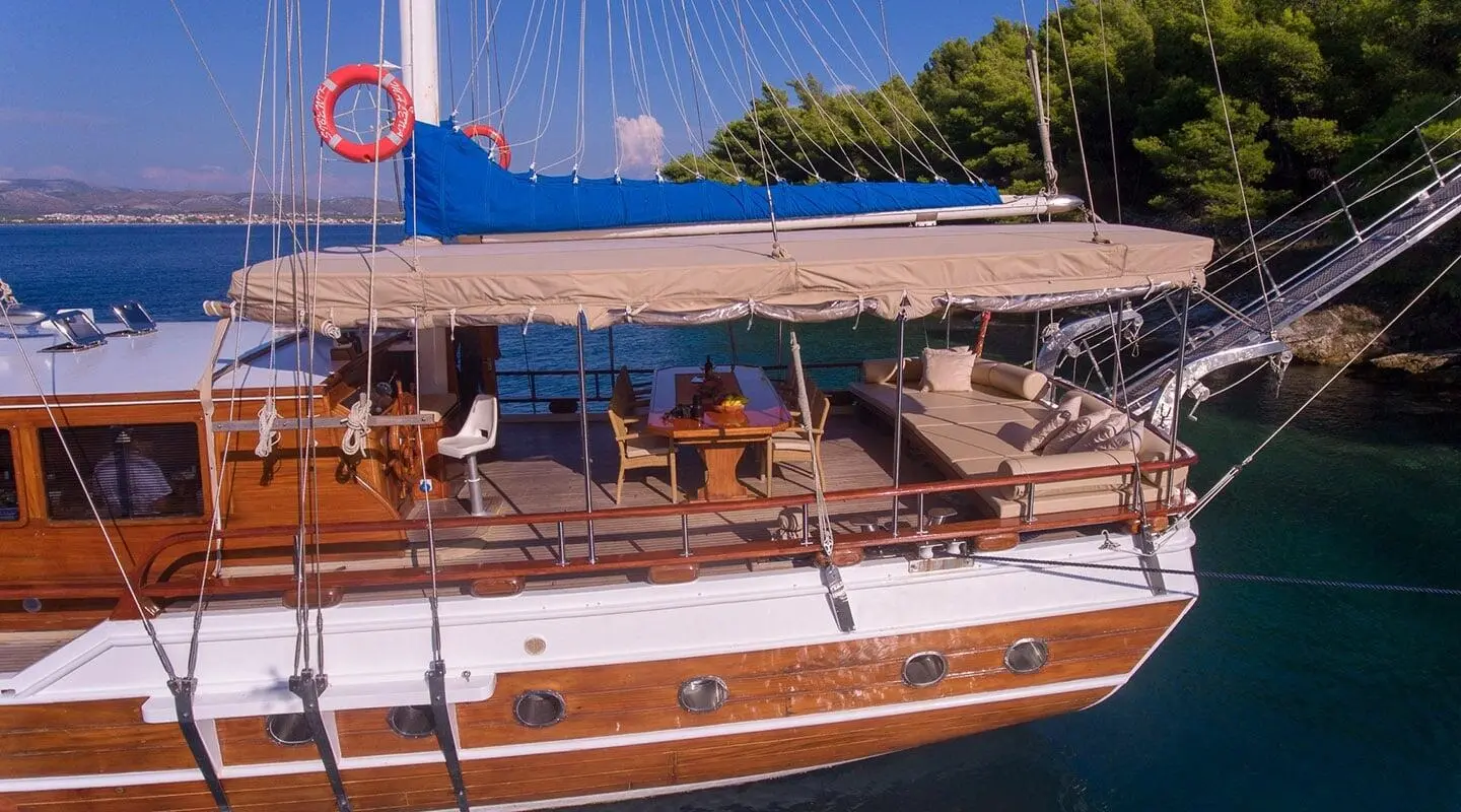 Malena yacht with a dark blue hull and polished wooden deck at sunset harbor scene