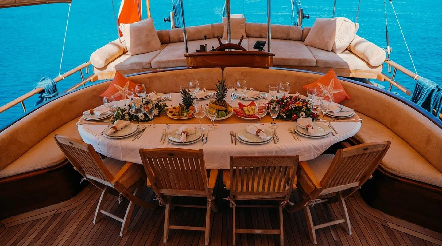 Wicked Felina yacht dining area at sunset with plates and chairs set