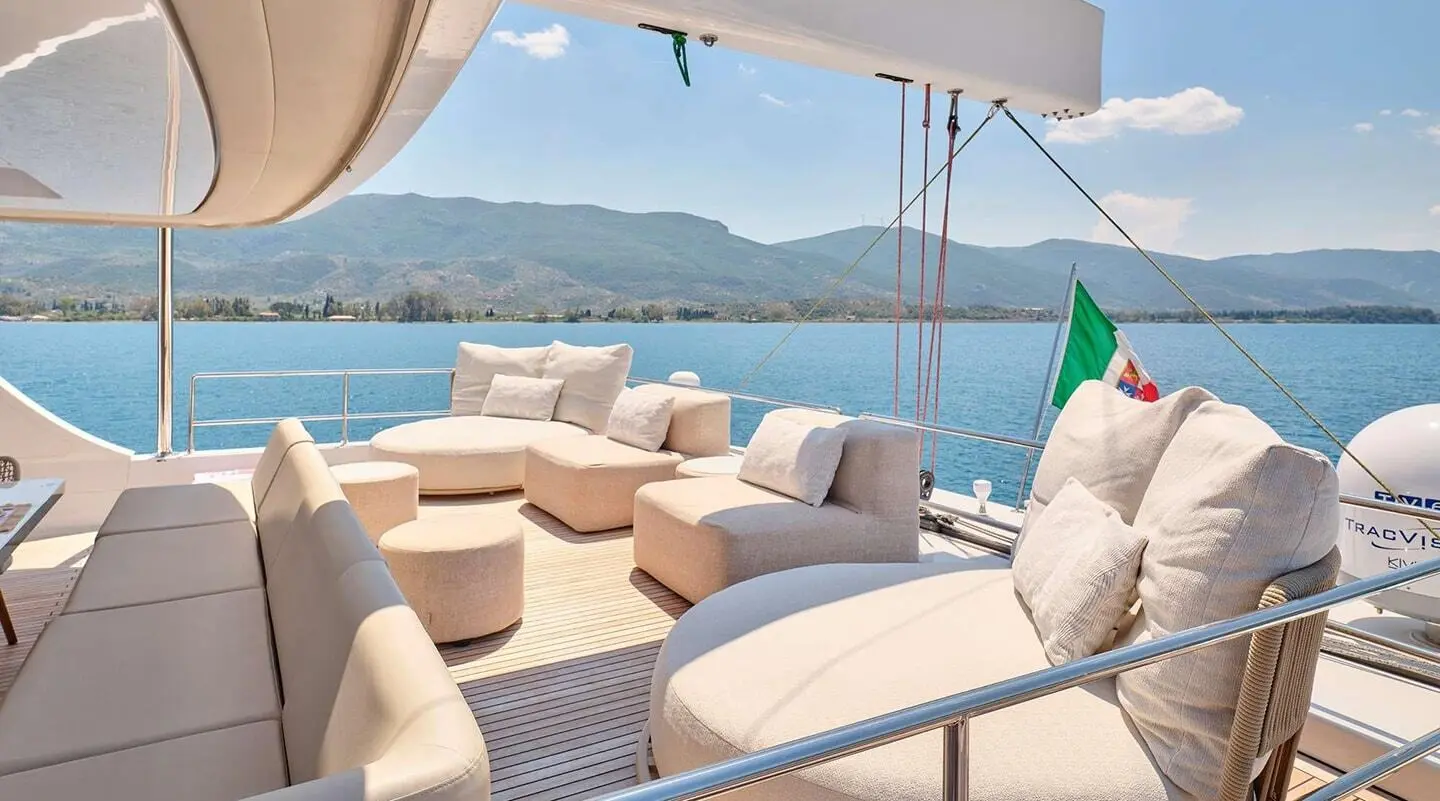 Yacht Genny lounge on deck with seating, cushions, and sea view at sunset