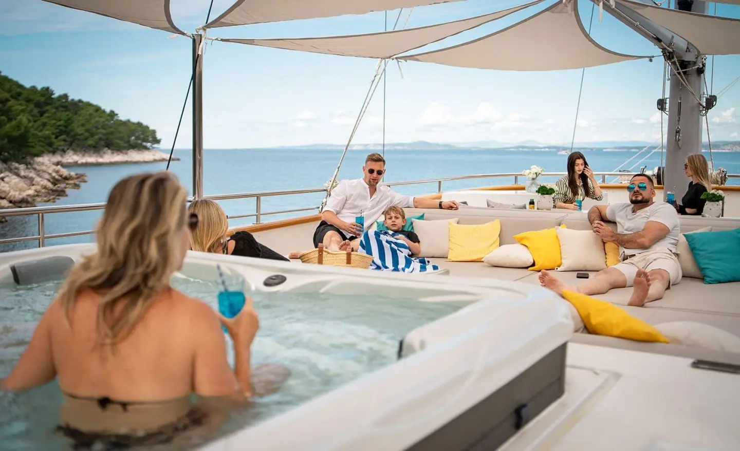 Dalmatino yacht on sun deck at sunset with guests lounging by a hot tub