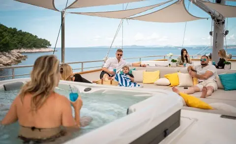 Dalmatino yacht on sun deck at sunset with guests lounging by a hot tub