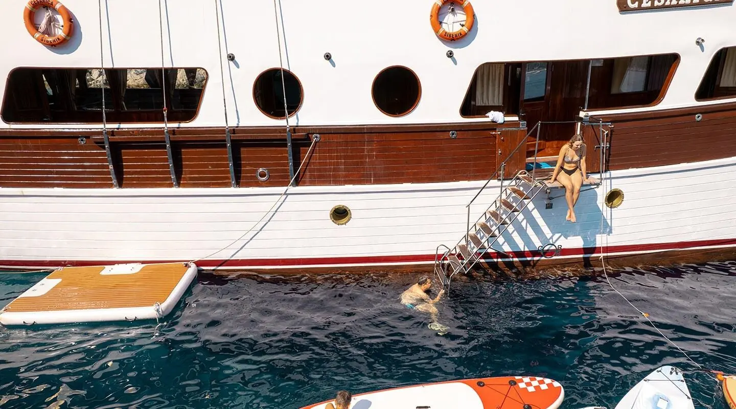 Cesarica luxury gulet at sunset with wooden deck rails and crew stairs descending to water