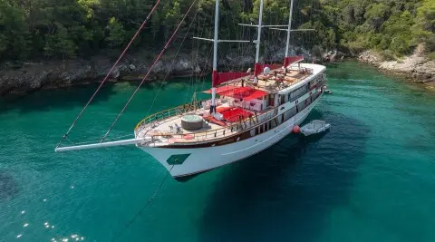 Yacht Barbara anchored in turquoise water with red seating and sails visible