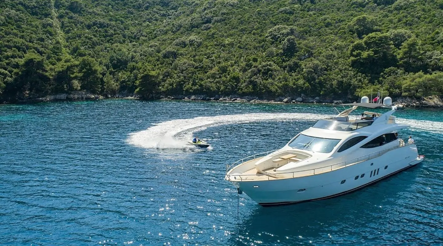 Salt yacht anchored near rocky coastline with clear blue water and small waves