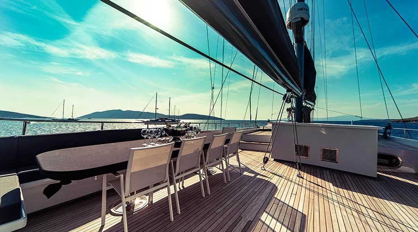 Luxurious yacht Virtuoso deck with seating and calm sea at sunset