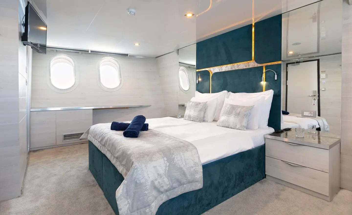 Yacht Yolo exterior deck with white and teal bedding, harbor lights visible
