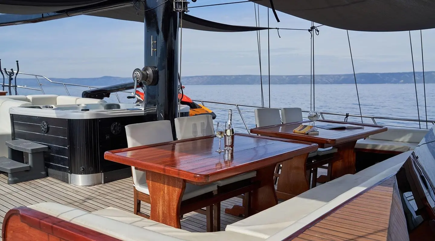 Gulet Stella Maris deck seating area with wooden table and benches under shade